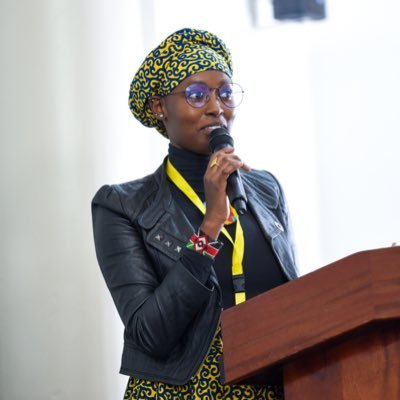 Marlene, a young black woman speaks into a microphone at a podium