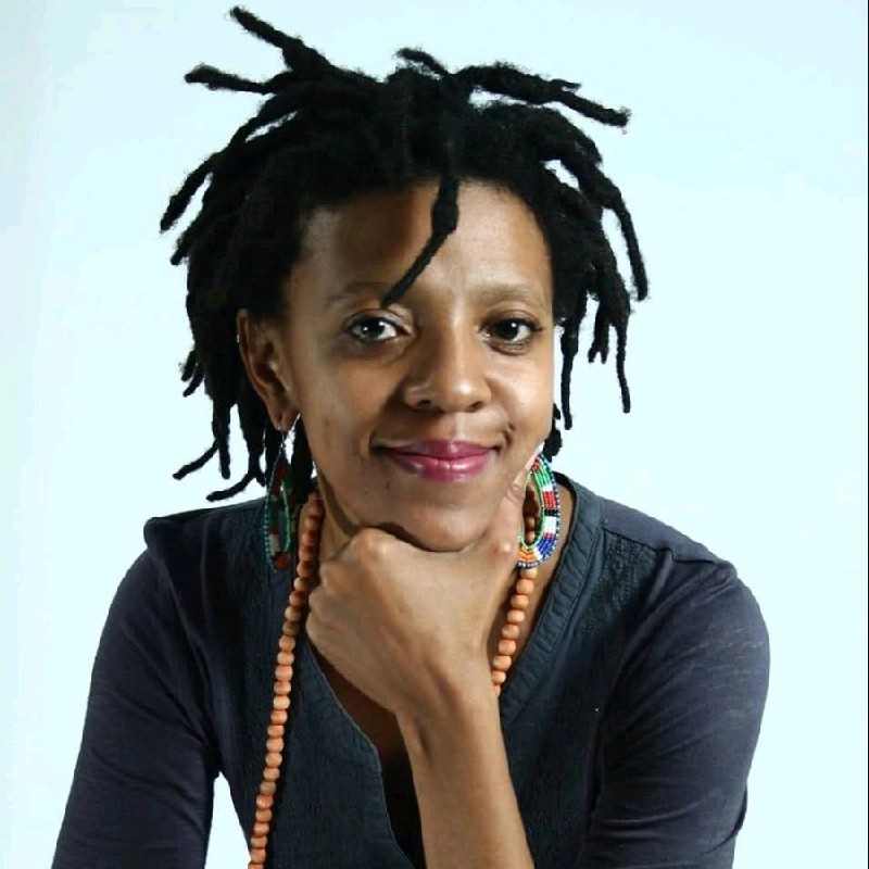 Kgauhelo Dube, a black woman with short dreadlocks smiles warmly at the camera